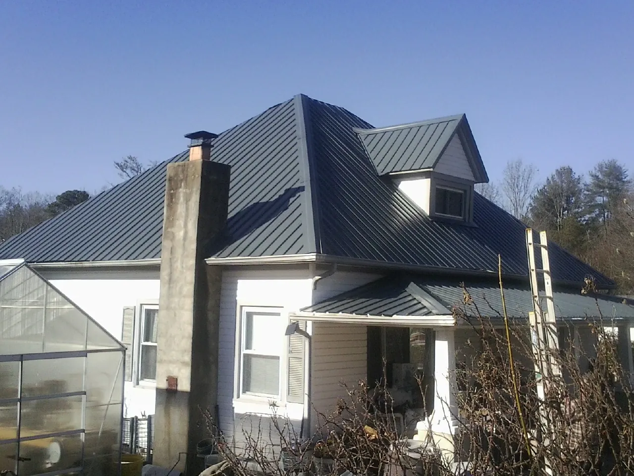 Dark blue standing seam metal roof on a white farmhouse with dormer — Slate & Tile Roof Repair by Roofing Brothers in Acampo