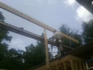 Carpenter setting a ridge beam over a new addition frame — Ice Dam Removal by Roofing Brothers in Acampo