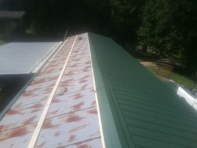 Old rusted panels beside newly installed green metal roofing — Wind Damage Roof Repair by Roofing Brothers in Acampo