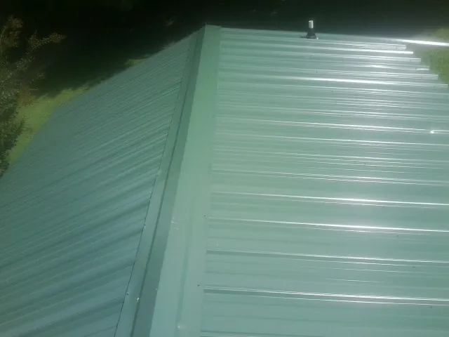 New green metal panels meeting at the ridge of a roof — Flat Roof Repair work by our crew in Acampo