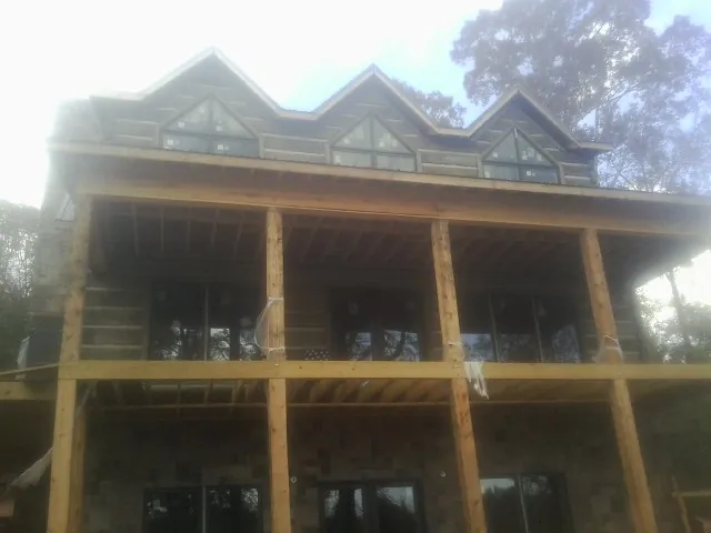 Dormers and porch framing on a large log home under construction — Roof Coating work by our crew in Acampo