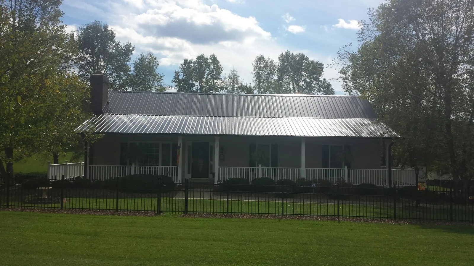 Gray metal roof on a brick ranch with a full width front porch — Gutter Guard Installation work by our crew in Acampo