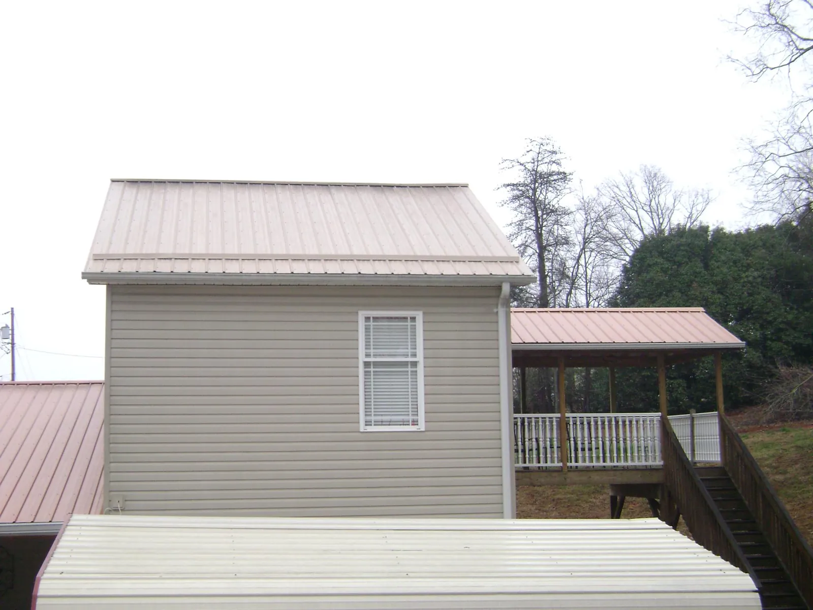 Tan metal roofs on a two story addition and attached porch, from a Roof Replacement job in Acampo